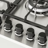 Cuisinière à gaz avec quatre boutons à l’avant, brûleurs sur le dessus, finition métallique.