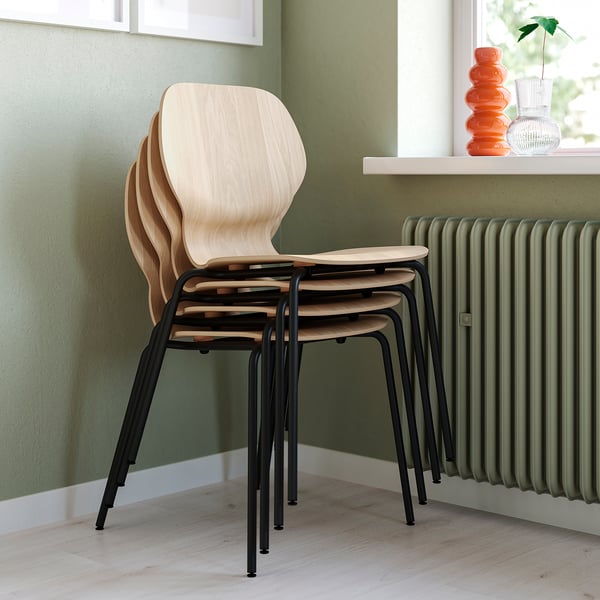 Quatre chaises en bois soigneusement empilées, adaptées à une utilisation en intérieur, conçues pour un assemblage facile et un empilage peu encombrant.