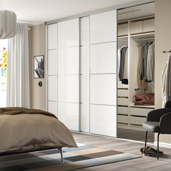 Chambre moderne avec une grande armoire à miroir, des vêtements soigneusement rangés et un éclairage doux.