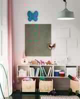 Chambre d’enfant avec étagères SMÅGÖRA. Étagères en bois avec des jouets et des livres. Décoration murale papillon bleu, suspension verte, rideaux colorés.