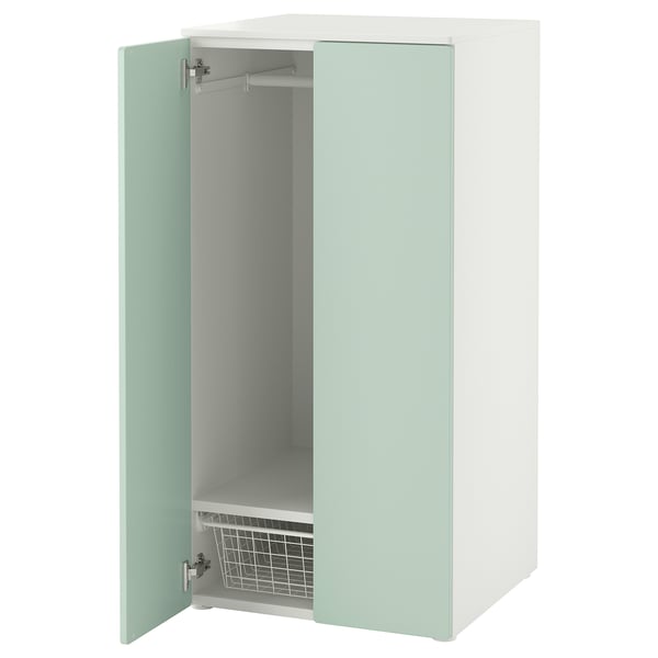 Une armoire SMÅSTAD vert clair avec une porte ouverte, révélant une étagère réglable et un panier en fil métallique.