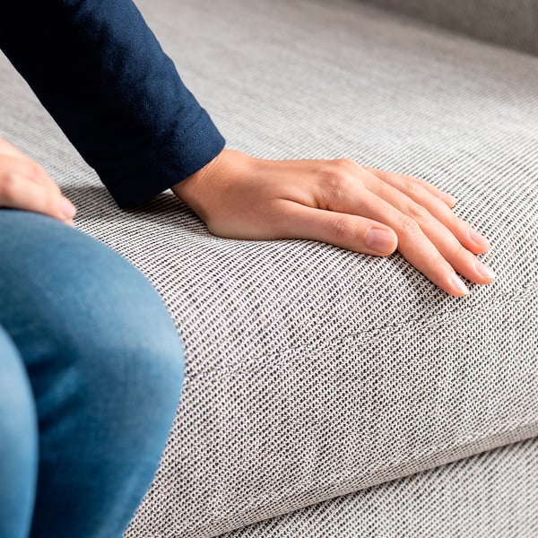 Personne teste un canapé doux et de haute qualité ; Sensation de confort moderne, mousse résistante, tissu facile d’entretien.