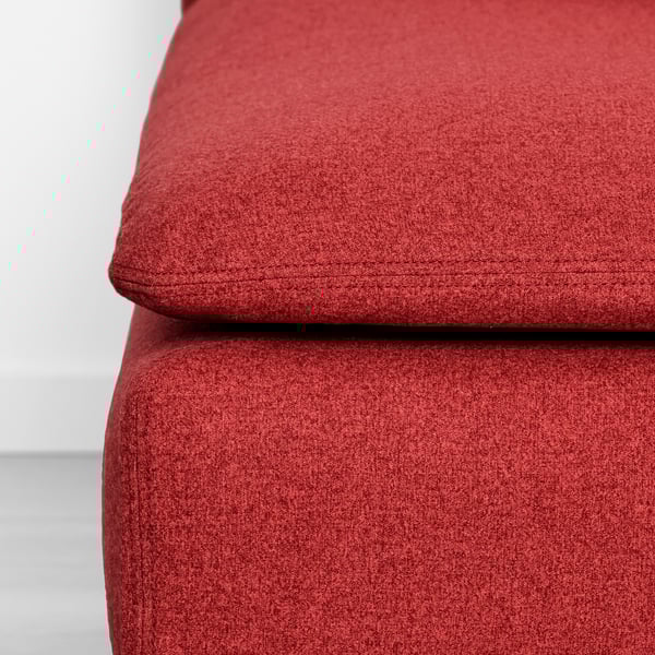 Gros plan d’un tissu rouge, probablement un coussin de canapé ou de chaise, présentant une texture détaillée et des coutures soignées.