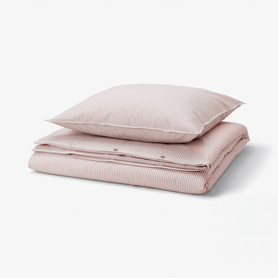 Un ensemble de housse de couette rayée rouge et blanche pliée en coton recyclé.