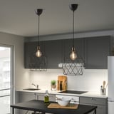 Cuisine moderne avec deux suspensions LED suspendues au-dessus de l’îlot, émettant une lumière blanc chaud.