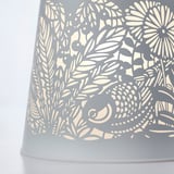 Lampe complexe en métal gris avec motif floral découpé pour un éclairage délicat.