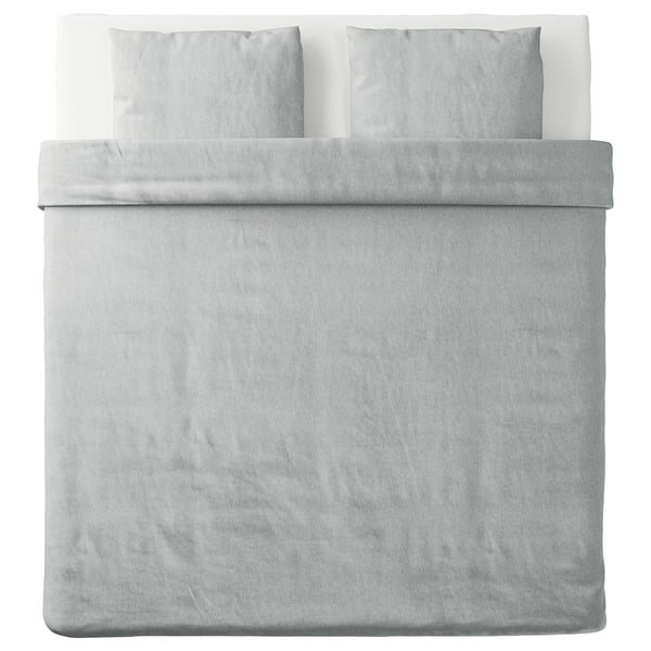 Un lit soigneusement fait avec une housse de couette SPJUTVIAL grise, en tissu jersey de coton doux.