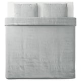 Un lit soigneusement fait avec une housse de couette SPJUTVIAL grise, en tissu jersey de coton doux.