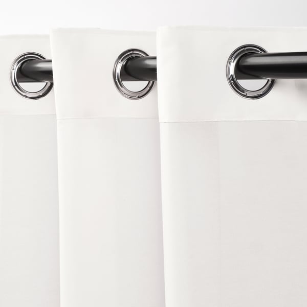 Des rideaux blancs transparents sont suspendus avec des œillets chromés, filtrant la lumière, offrant de l’intimité.