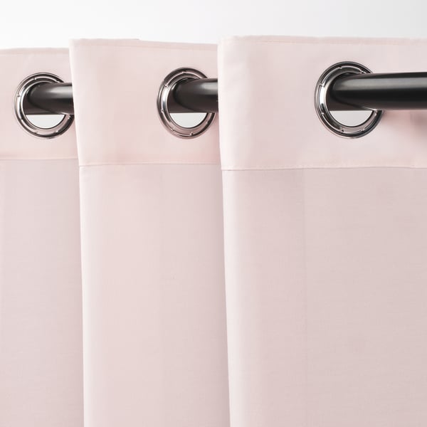 Deux rideaux rose clair avec des œillets argentés sont suspendus à une tringle noire, mettant en valeur leur tissu transparent et leurs plis gracieux.