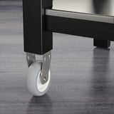 Gros plan du chariot Pied robuste en métal noir avec une roue lisse et grise pour un déplacement facile. La qualité des matériaux et de l’artisanat est évidente.