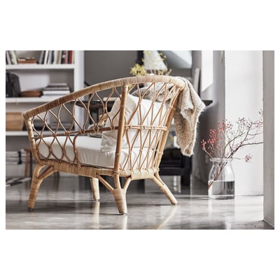Chaise moderne en osier de couleur naturelle avec coussins, placée dans une pièce minimaliste.