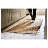 Personne marchant sur un tapis beige avec des armoires beiges.