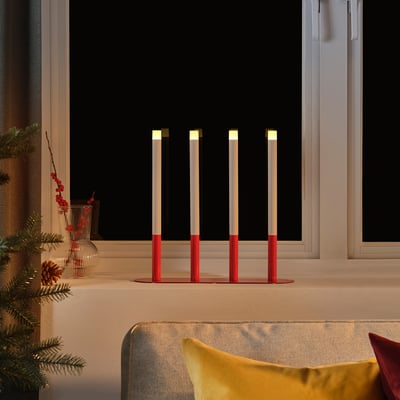 Bougies LED STRÅLA rouges, design moderne, sur le rebord de la fenêtre à côté du canapé.