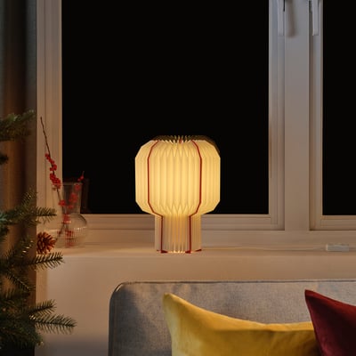 Lampe STRÅLA : ivoire avec des lignes rouges, lueur chaleureuse, décor festif.