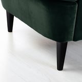 Fauteuil à oreilles en velours vert avec pieds en bois foncé, rembourrage de haute qualité, texture luxueuse, design confortable.