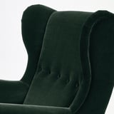 Fauteuil à oreilles en velours vert foncé à l’aspect moelleux et accueillant et aux lignes douces et incurvées. Le dos haut soutient le cou et la tête pour plus de confort.