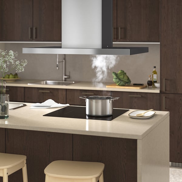 Cuisine moderne avec hotte de cuisine, lumières LED et casseroles à vapeur. Comptoirs, armoires en bois et tabourets beiges.