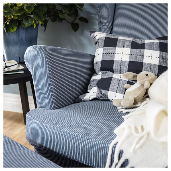 Fauteuil rayé bleu et blanc avec coussin à carreaux et ours en peluche. Configuration confortable du salon.