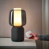 Personne tenant la lampe de haut-parleur SYMFONISK télécommandée sur la table.