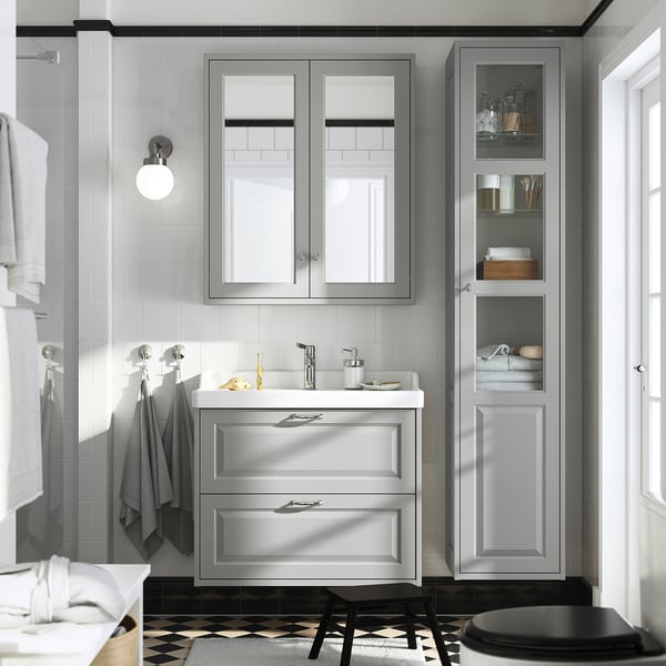 Salle de bain moderne avec armoire gris clair TÄNNFORSEN, lavabo de style marin, toilettes noires, carrelage à motifs et serviettes murales.