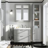 Salle de bain moderne avec armoire gris clair TÄNNFORSEN, lavabo de style marin, toilettes noires, carrelage à motifs et serviettes murales.