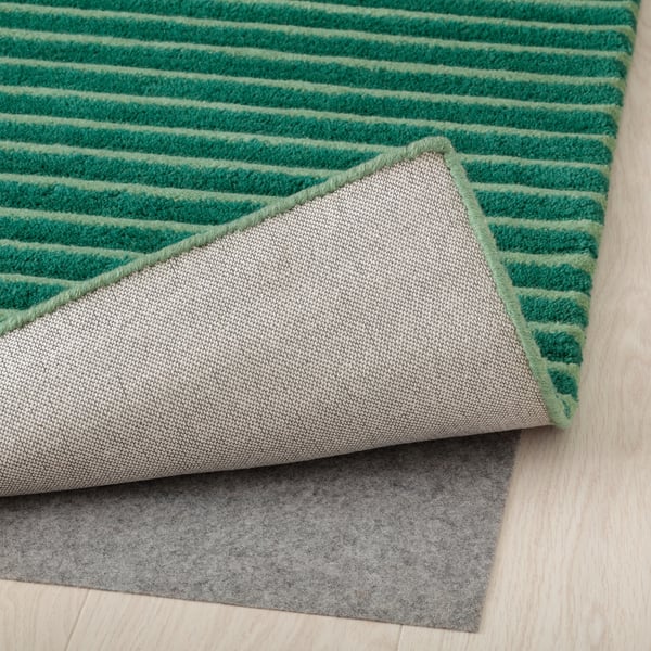 Tapis à rayures vertes avec sous-couche antidérapante pour plus de sécurité et de confort.