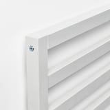 Gros plan d’un cadre de lit propre, blanc et moderne avec des vis métalliques apparentes, mettant en valeur l’artisanat et le design simple.