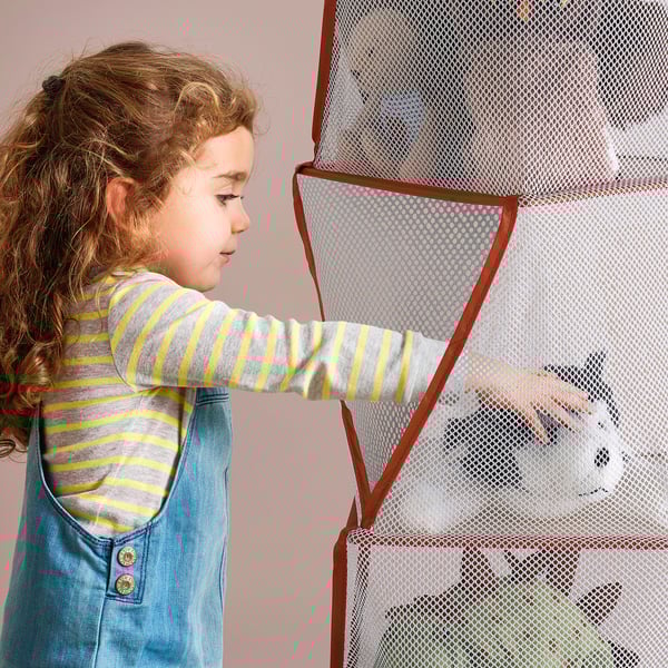 Enfant qui plonge la main dans un organisateur de jouets en maille avec 5 compartiments. L’organisateur est léger et pliable, conçu pour un simple rangement et nettoyage.