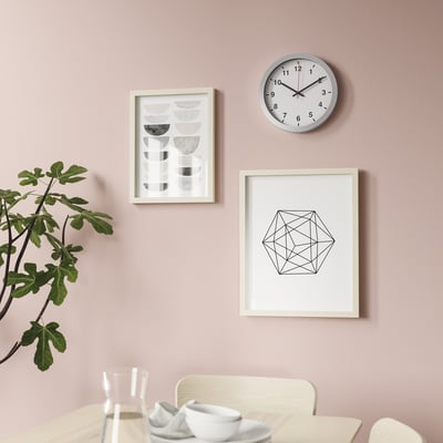Une horloge murale élégante au design simple. Il est silencieux, avec des chiffres noirs clairs sur une face blanche, indiquant qu’il est alimenté au quartz.
