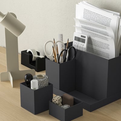Un organisateur de bureau TJENA noir avec plusieurs compartiments pour le rangement. Il est fait de papier recyclé et a un design moderne et minimaliste.