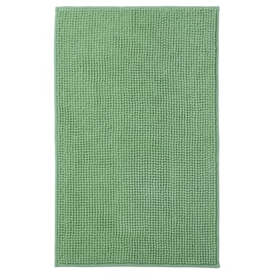 Un tapis de bain TOFTBO vert. Il est rectangulaire, doux et fabriqué à partir de polyester recyclé avec une surface texturée.