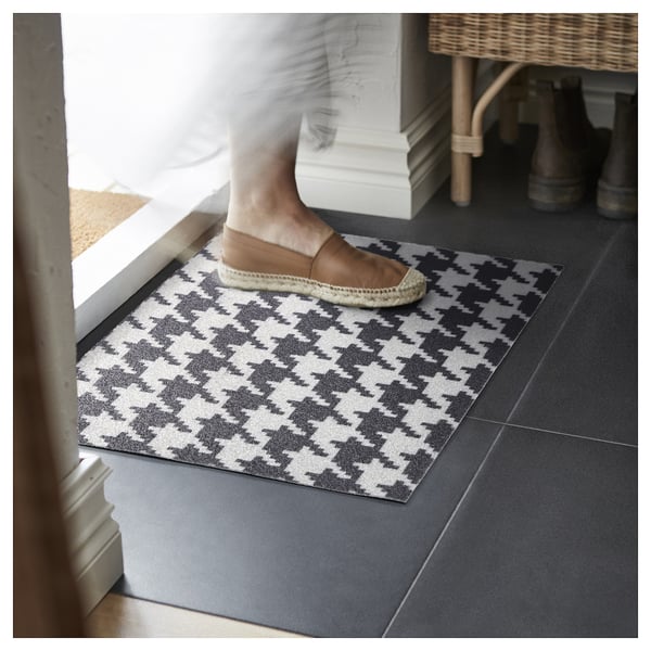 Personne marchant sur le paillasson TOMTRÄTT à motifs noirs et blancs par porte.