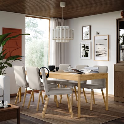 Salle à manger moderne avec table et chaises TONSTAD blanc cassé, accents de bois, éclairage élégant, art et plantes.