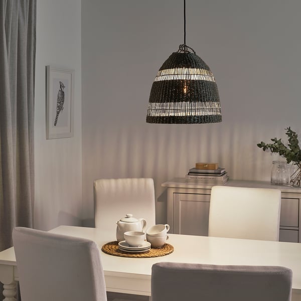 Une salle à manger confortable avec une suspension en jonc de mer projetant une lumière chaude sur une table avec une théière et des tasses.
