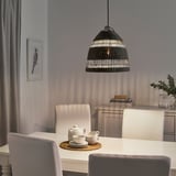 Une salle à manger confortable avec une suspension en jonc de mer projetant une lumière chaude sur une table avec une théière et des tasses.