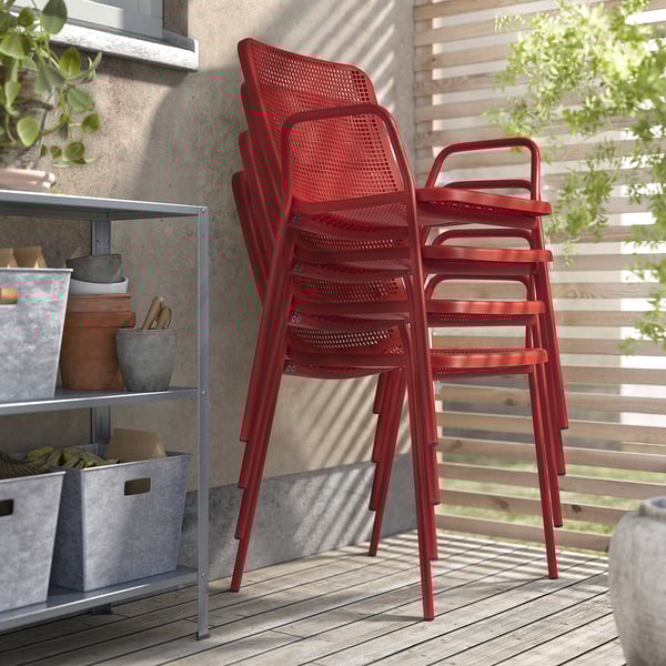 Deux chaises d’extérieur TORPARÖ rouge vif soigneusement empilées, présentant une construction en plastique et en acier durable et facile à nettoyer, idéales pour une utilisation sur la terrasse.
