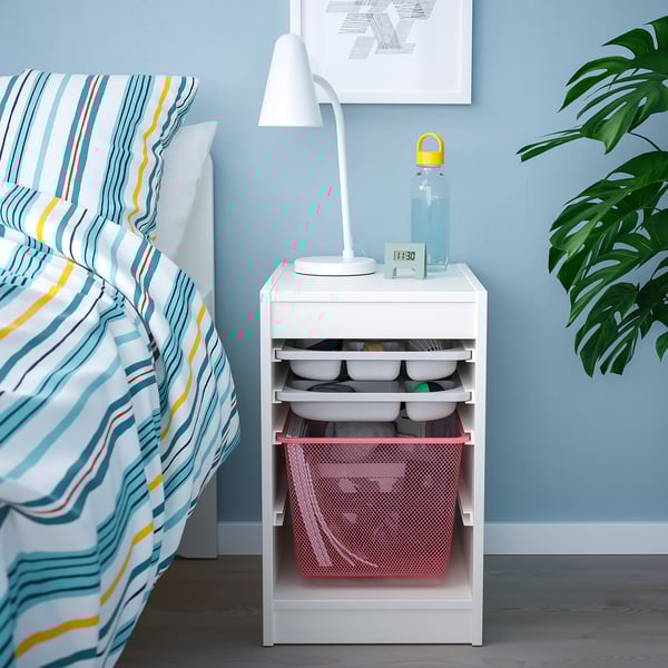 Unité de chevet TROFAST avec lampe, bouteille, horloge ; couvre-lit coloré, plante.