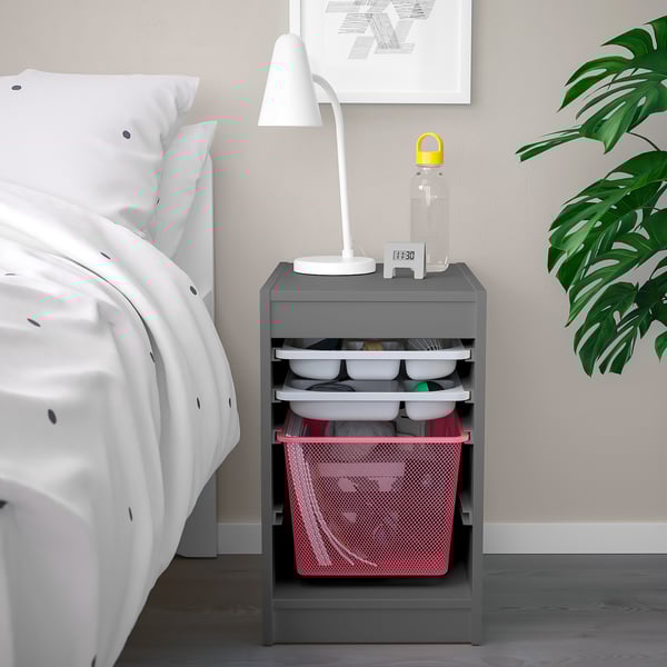 Meuble de rangement TROFAST gris par lit avec bacs roses et lampe.