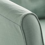 Gros plan d’un coin de fauteuil gris rembourré. Montre des coutures soignées et une texture de tissu de qualité.
