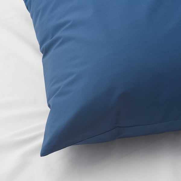 Taie d’oreiller bleue sur literie blanche, texture nette mais douce visible.