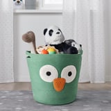 Le panier en coton vert avec un motif de hibou contient des jouets en peluche sur un tapis à pois gris.