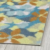 Tapis abstrait aux couleurs vives, posé sur un plancher en bois. Texture douce, motifs complexes visibles.