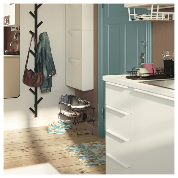 Entrée avec tapis VÄLFÄRD, motif floral bleu et orange, parquet, étagère à chaussures, veste et sac à main.