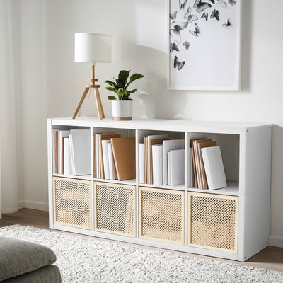 Un organisateur de cube våltning blanc avec des livres et des décorations. Il comprend une lampe, une plante et une affiche de papillons.