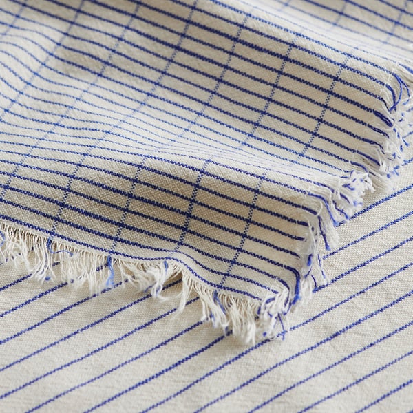 Couverture rayée beige et bleue à franges.