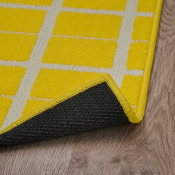 Tapis à carreaux jaune vif avec carrés blancs, support antidérapant noir, confortable et sûr.