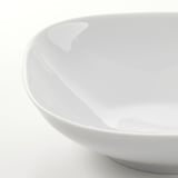 Gros plan d’un plat en porcelaine lisse et blanche montrant une finition brillante et un bord uniforme et robuste.