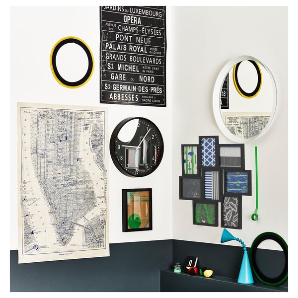 Présentoir mural avec des cadres, des miroirs et des cartes variés, présentant un mélange de styles de décoration. Comprend une horloge ronde, des images colorées et des œuvres d’art murales.