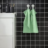Serviettes vertes près de l’évier avec articles de toilette.